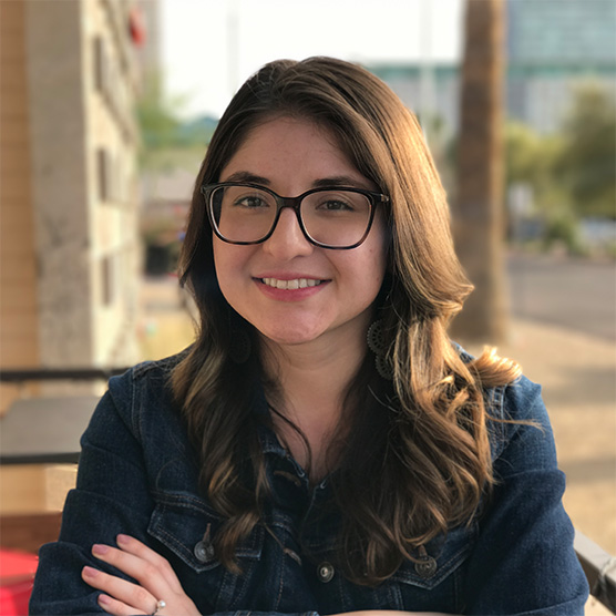 Jessica Casillas wearing a jean jacket and smiling in Papago Park on a sunny day.